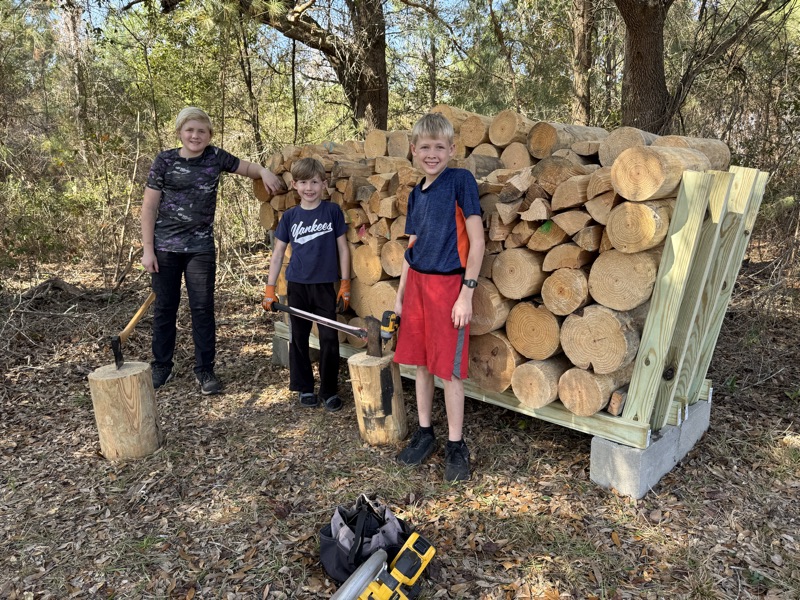 The brothers with a rack they built, filled with split and round wood.