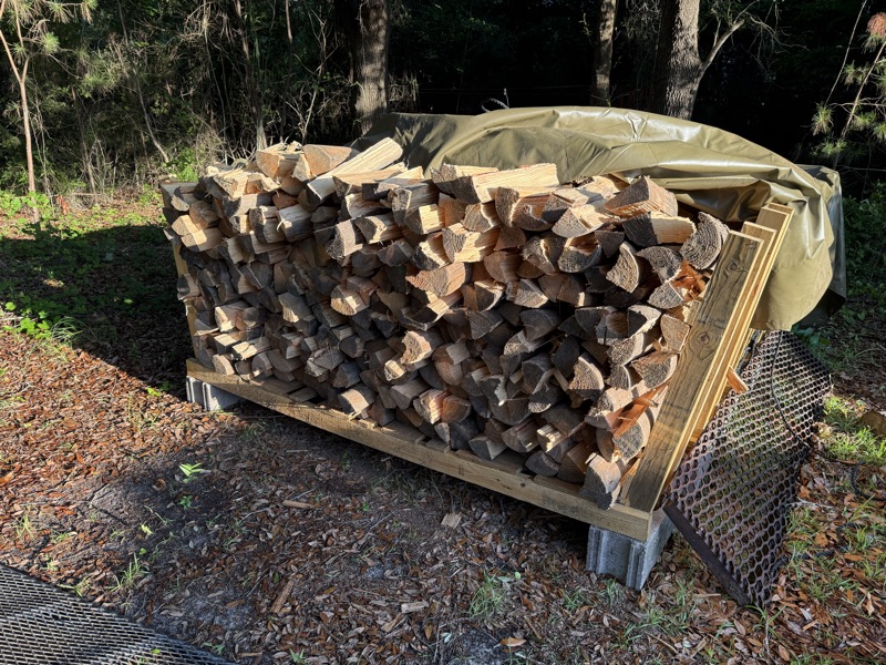 A face cord of split wood on a rack the boys built, under the customer's own tarp.